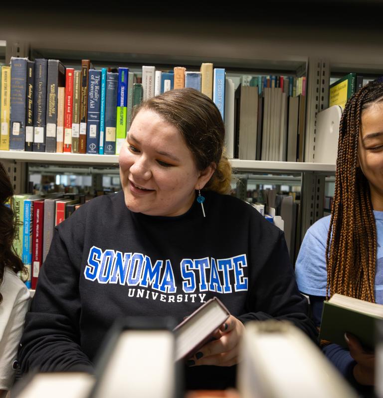 Three students looking at books and wearing SSU gear