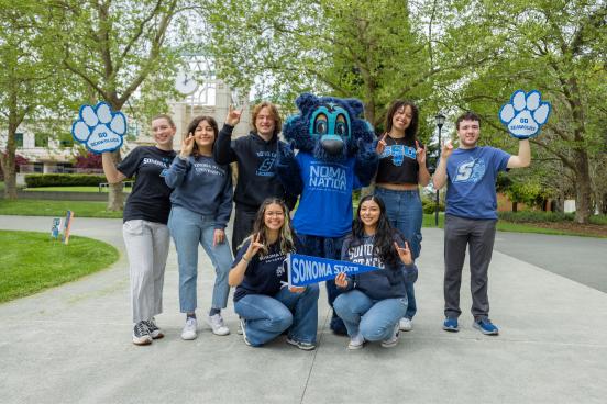 Students in a group smiling and standing next to Lobo the mascot