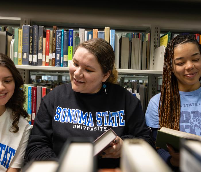 Three students looking at books and wearing SSU gear